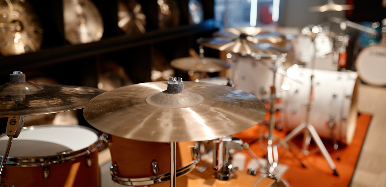 Selective view on drum set and several golden cymbal plates in music shop. Musical instrument assortment in art store